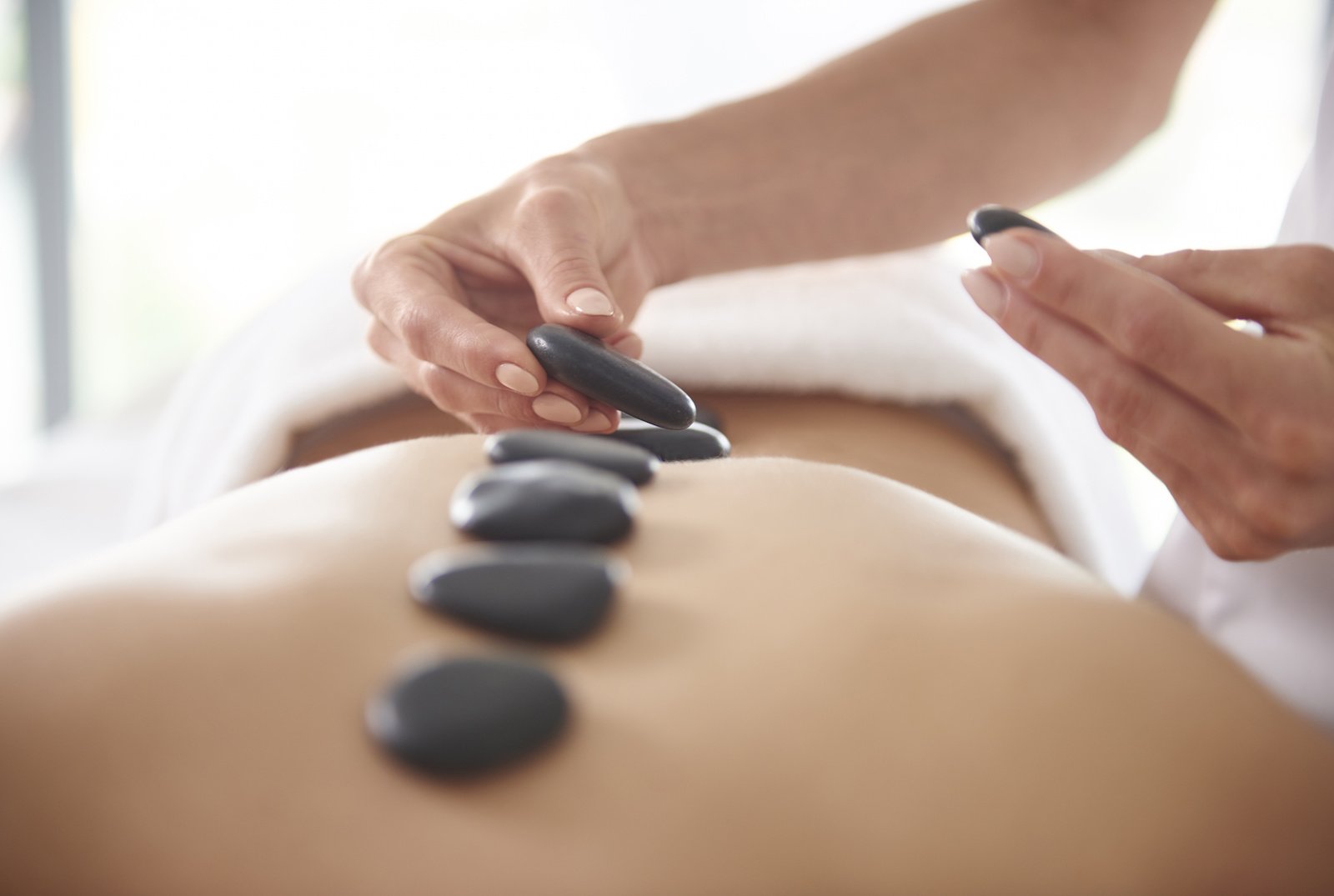 Hot stone massage benefits: A massage therapist places stones on a woman's back