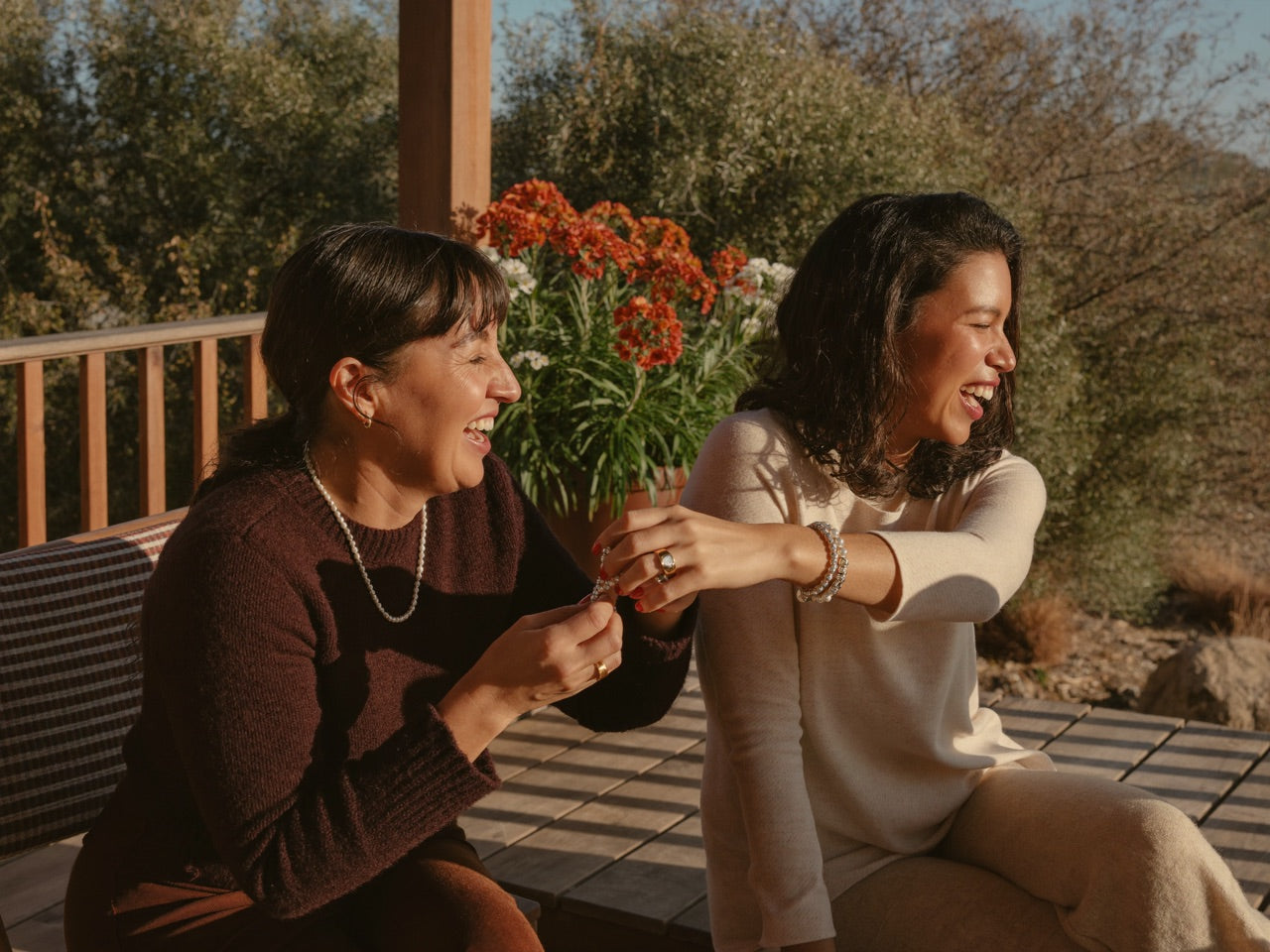 Two friends sharing a crystal bracelet on a sunlit porch